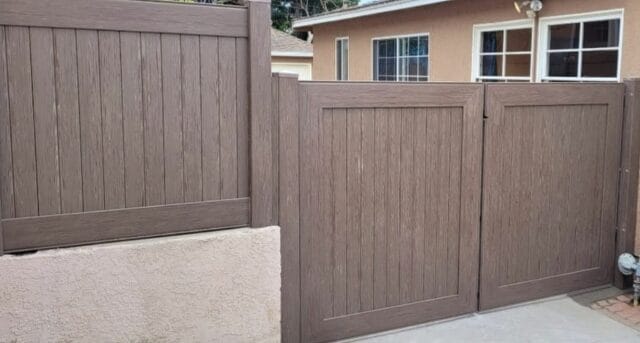 Brown vinyl fence with vertical slats and borders leading, along with modern suburban home in the background.