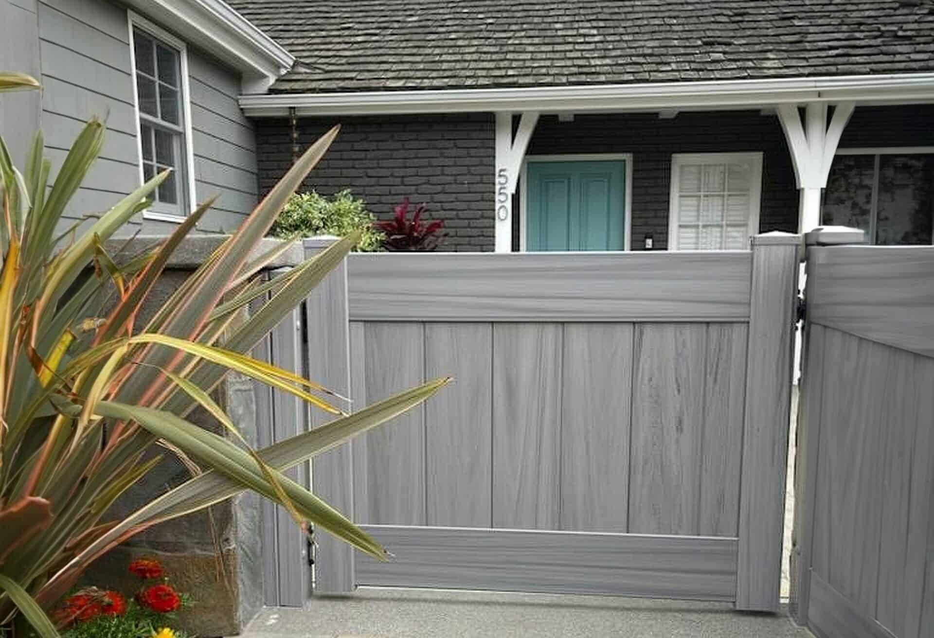 Vinyl coastal cedar colored fence with small gate leading into main entrance of modern suburban home