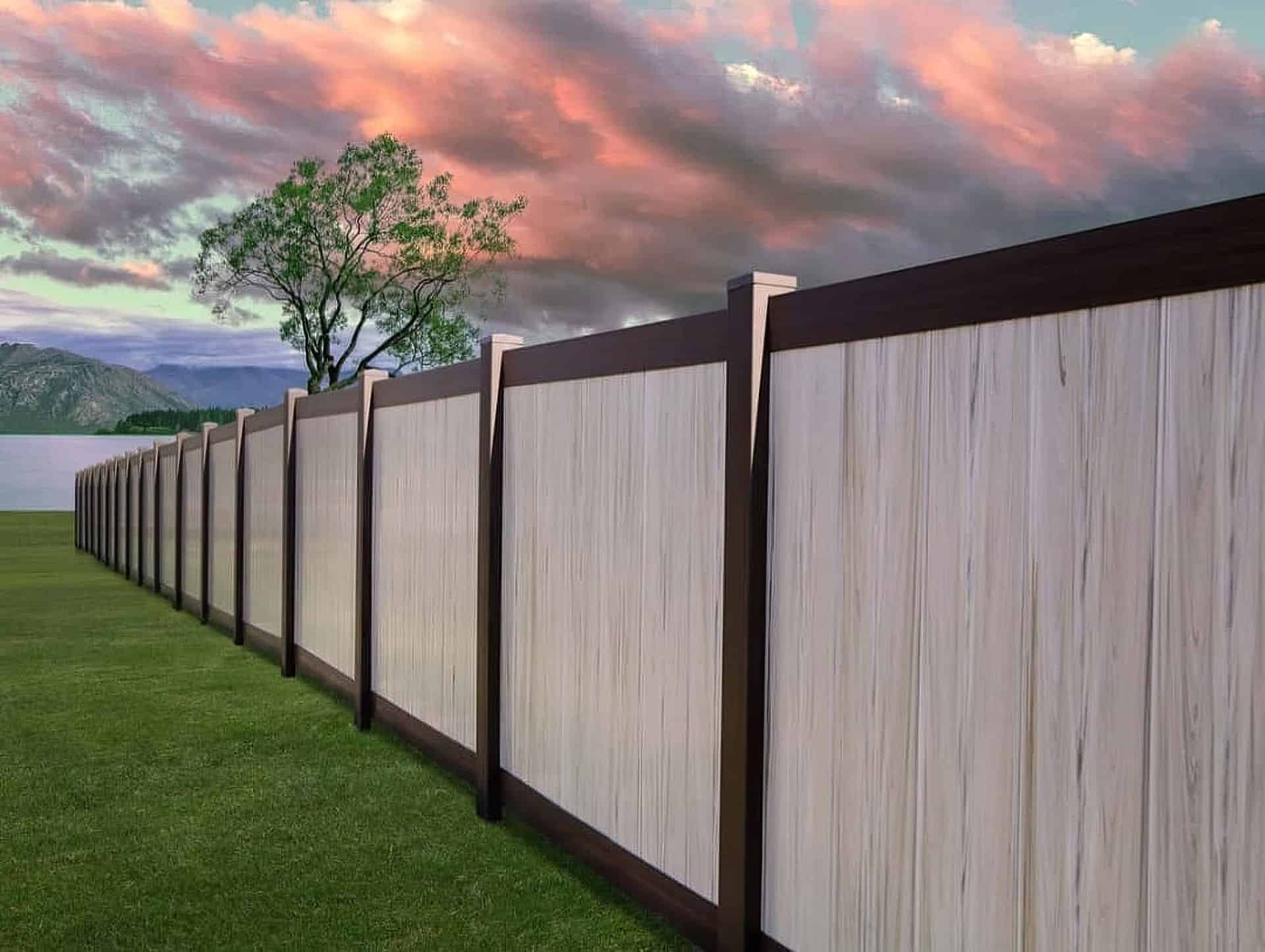 Vinyl weathered aspen colored fence in front of large tree on grassy lawn with a picturesque view of the mountains.