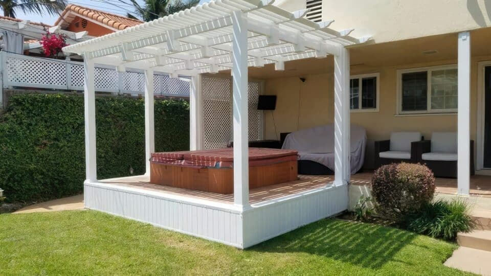 Outdoor furniture vinyl patio cover & jacuzzi on concrete floor, front lawn & hedge wall create a relaxing outdoor oasis.
