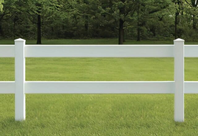 Vinyl 2-rail ranch fence in country setting, open field, grassy lawn, trees in background.