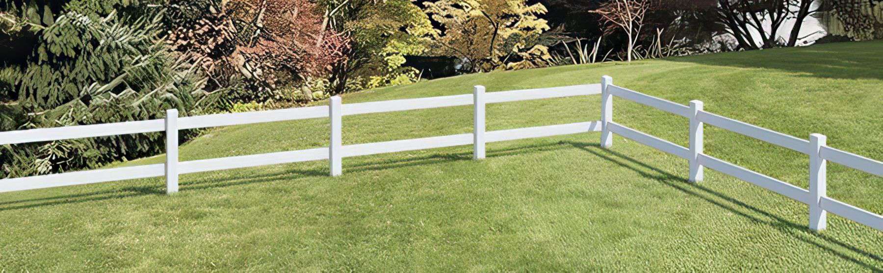 Vinyl 2-rail ranch fence in a serene country setting with a farmhouse, open field, lush lawn, and trees in the background.