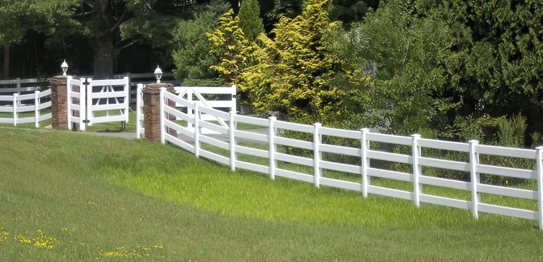 Vinyl 4-rail ranch fence under a clear sky with double gate and trees in the background.