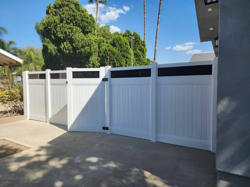 Vinyl & acrylic privacy fence, concrete floor, trees & houses in background - a modern outdoor scene