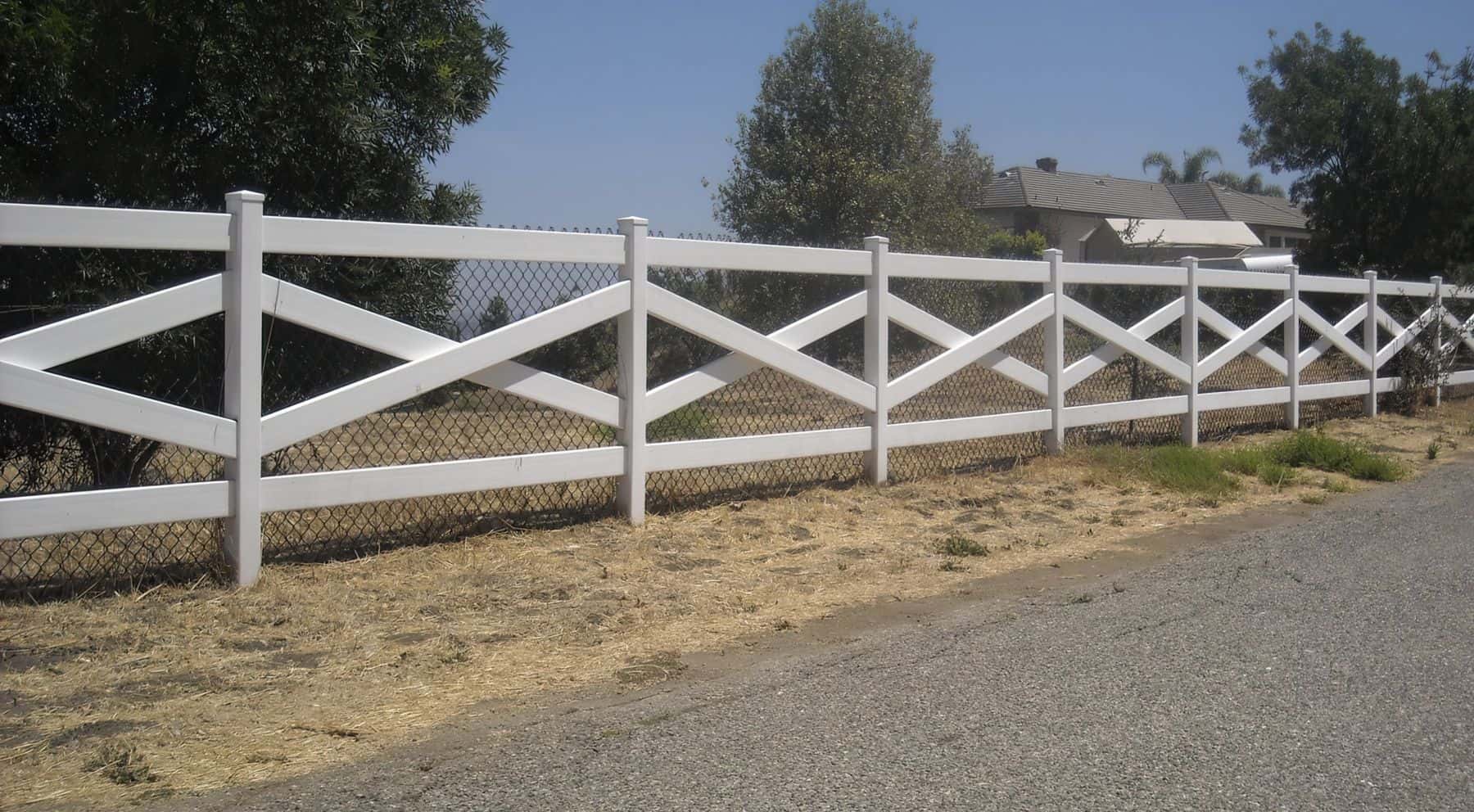 Vinyl cross rail ranch style fence beside the road with a chain link fence behind it to further discourage trespassing