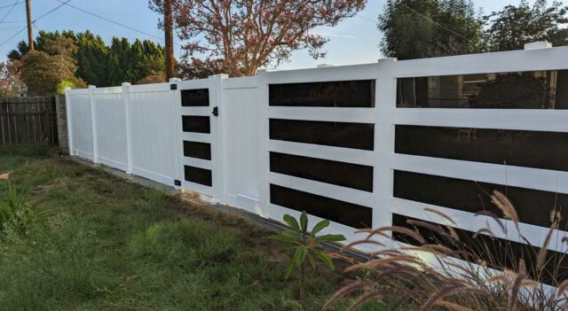 Vinyl fence and gate. White vinyl panels with acrylic around green grass.
