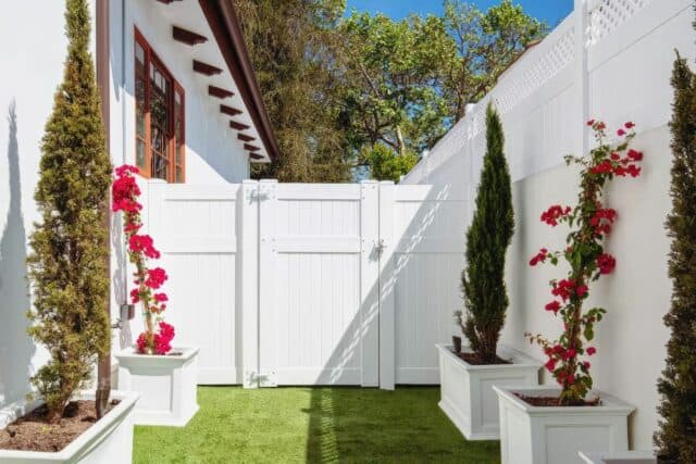 Cute waist length vinyl doors leading into side passage from front lawn with small plants and lush grassy lawn