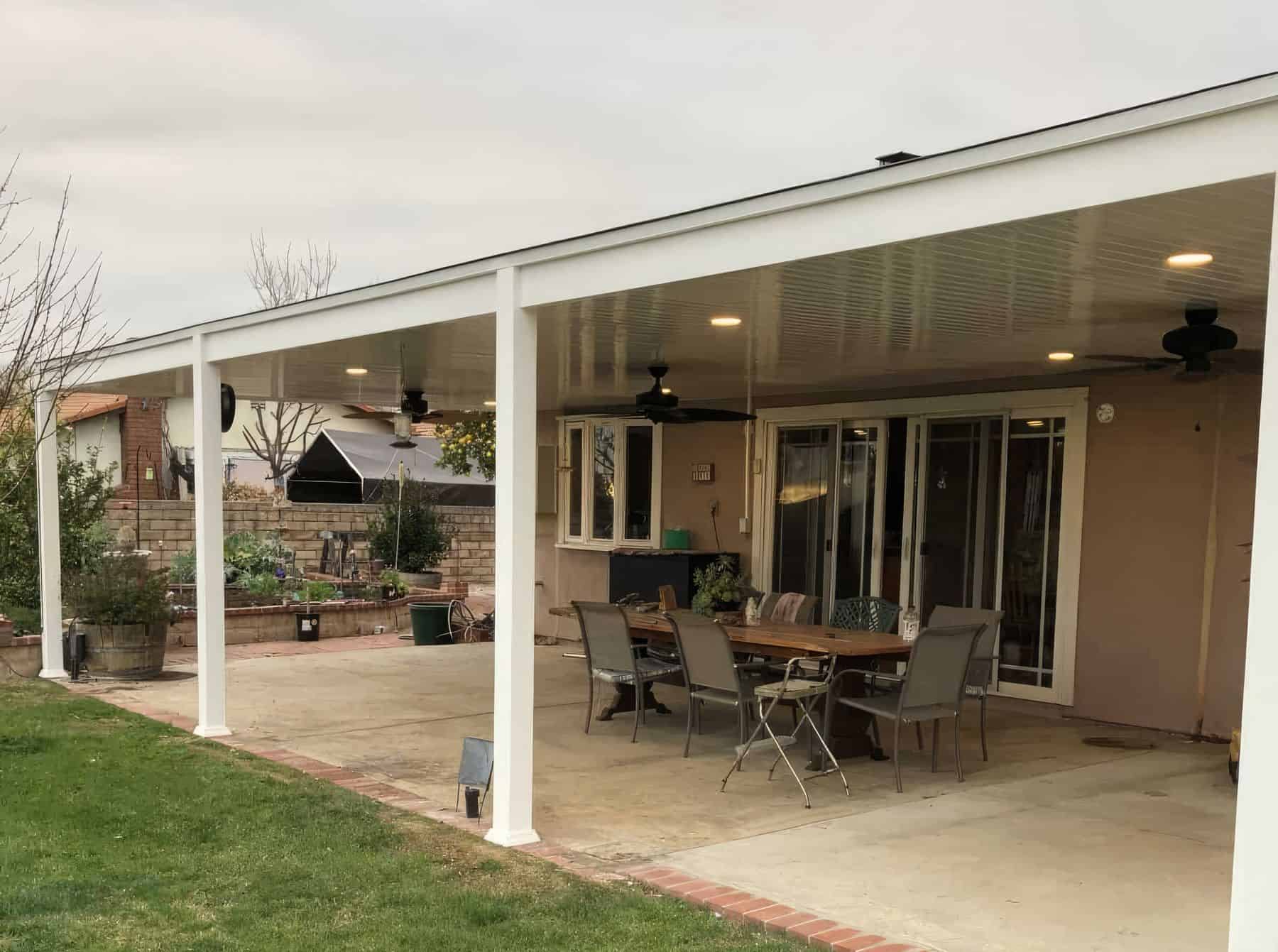 Outdoor vinyl patio awning, concrete floor, glass windows, ceiling fans, and outdoor tables.