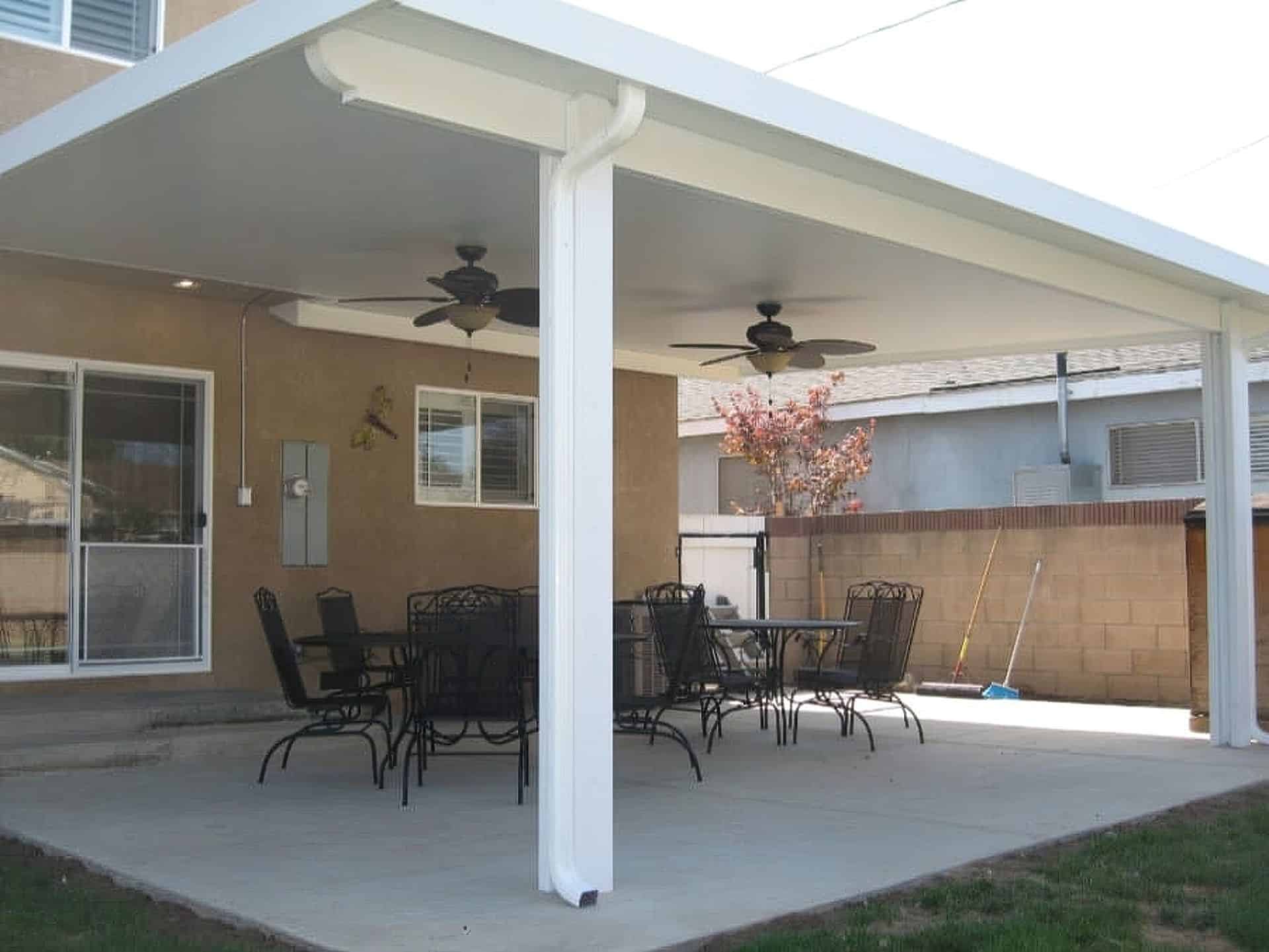 "Vinyl patio awning & glass door on concrete floor. Ceiling fans above. Serene outdoors with trees in the background."