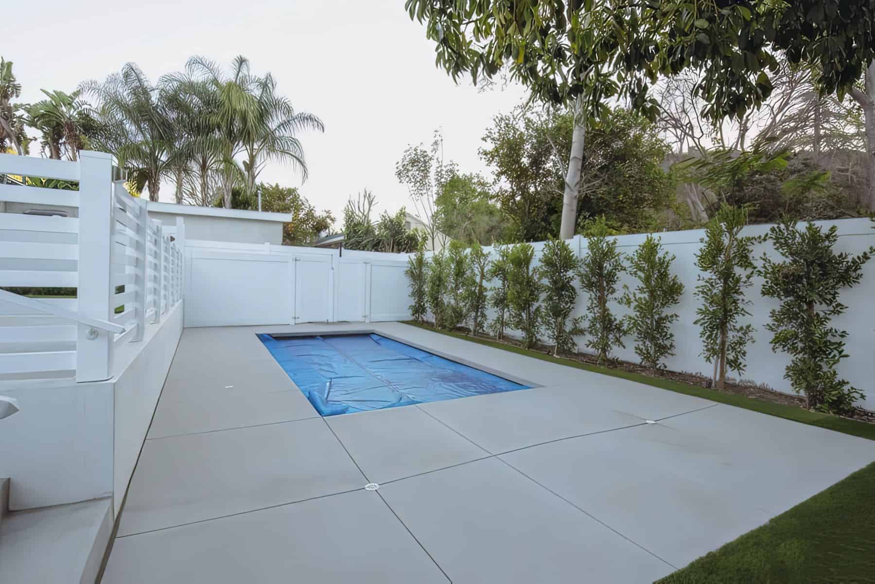 Vinyl pool fence separating marble flooring and comfortable seating from the grassy lawn from the backyard