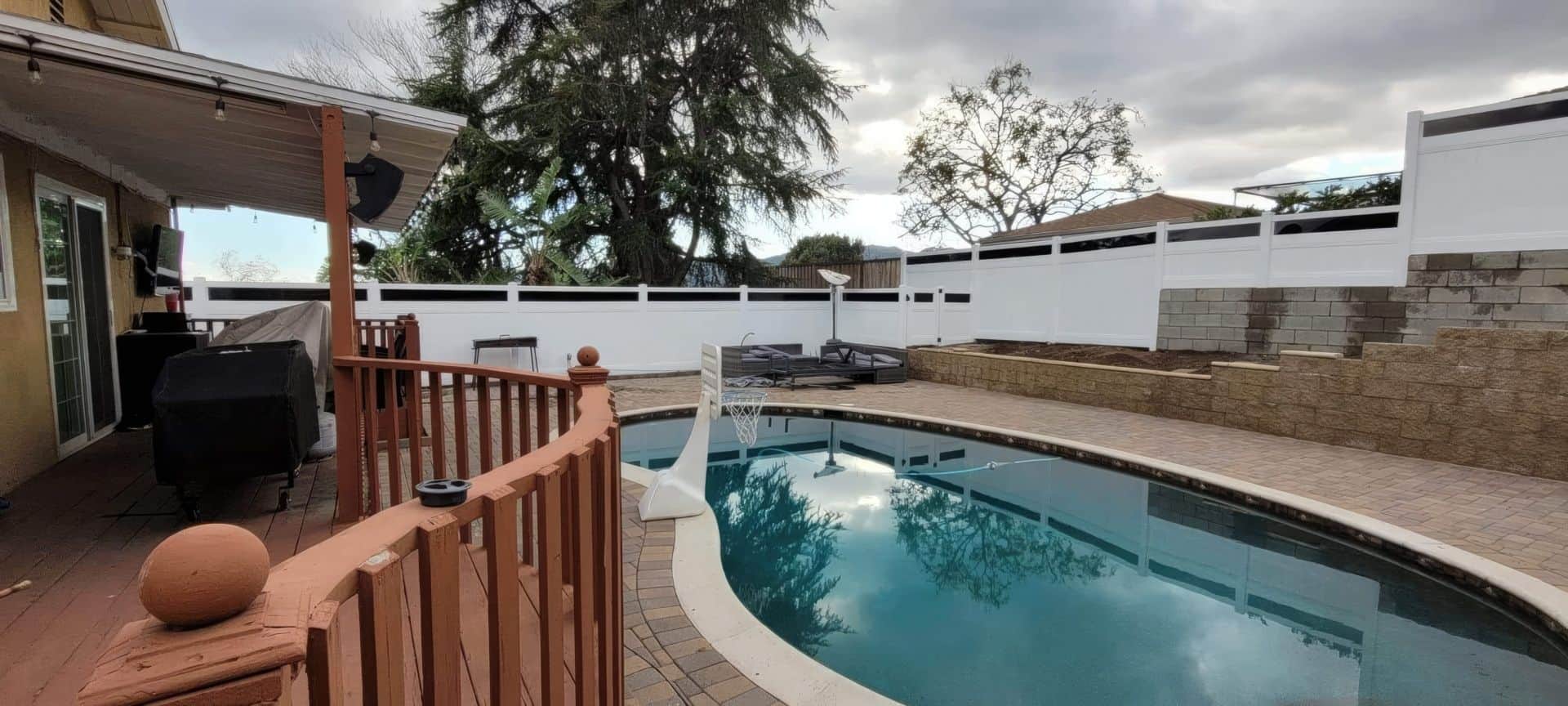 Vinyl pool fence with gate keeping the pool area with concrete boundary walls and flooring from the rest of the house.