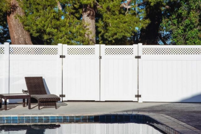 Vinyl privacy and lattice fence on top of elevated garden in backyard connected to another privacy fence.