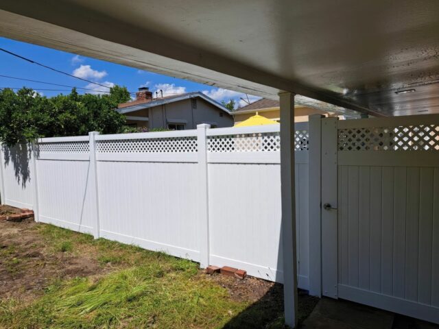 Vinyl privacy and lattice fence separating other small suburban home from another home’s backyard preparing to grow grass.