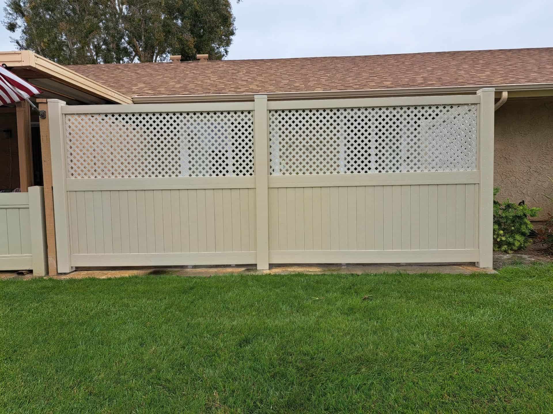 Vinyl privacy and lattice fence with gate giving entrance into small garden with trees and multiple plants