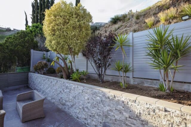 Vinyl privacy horizontal fence on an elevated garden of backyard retreat that also features small trees and plants