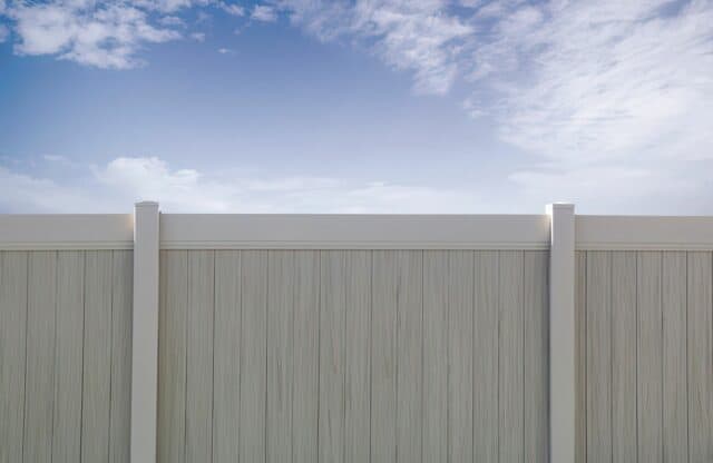 Vinyl privacy two-tone fence with white borders and a beige centre surrounding backyard overlooking clear skies.