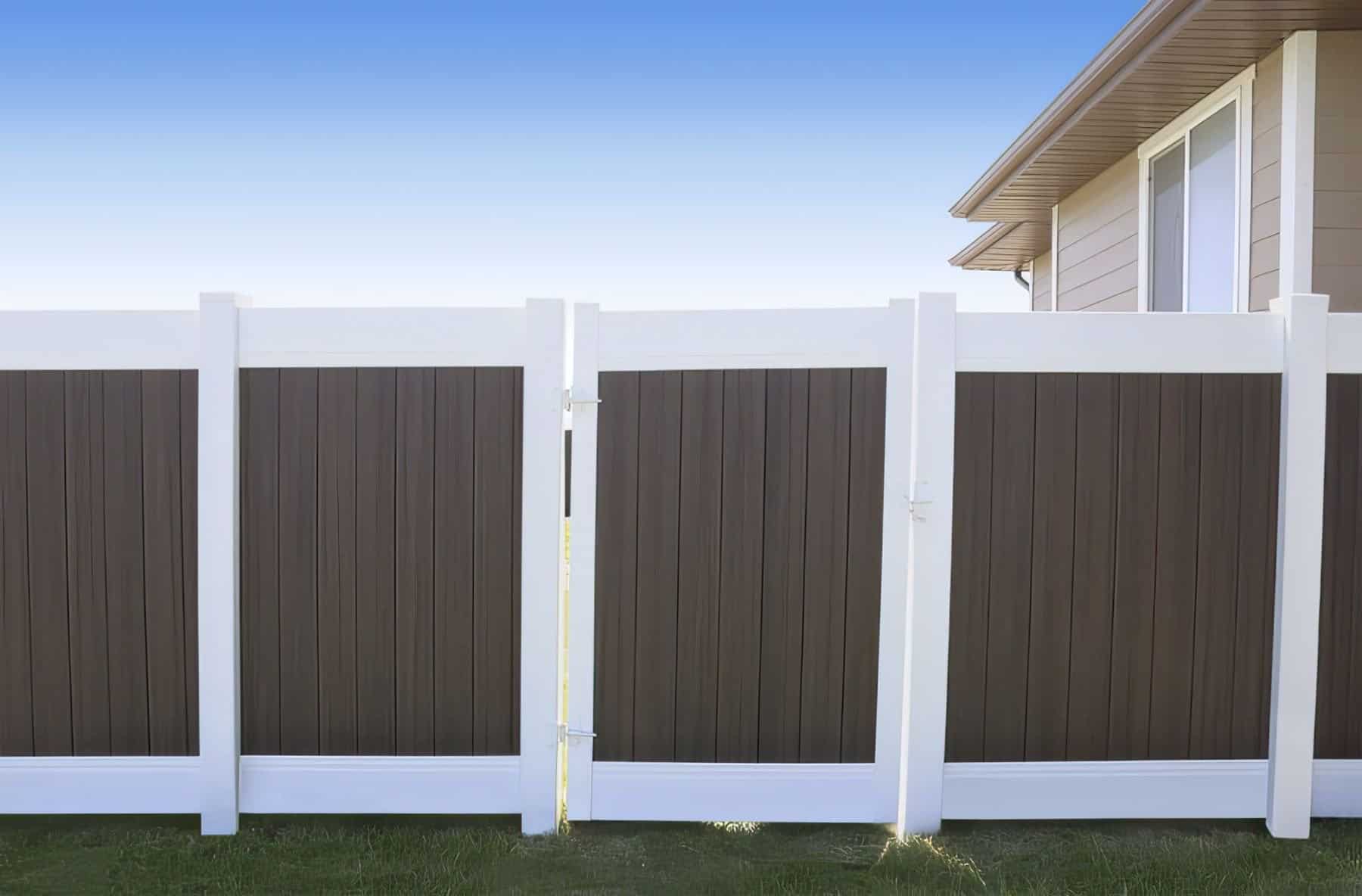 Vinyl privacy two-tone fence with thick white borders and a contrasting dark brown centre along with gates leading inside.