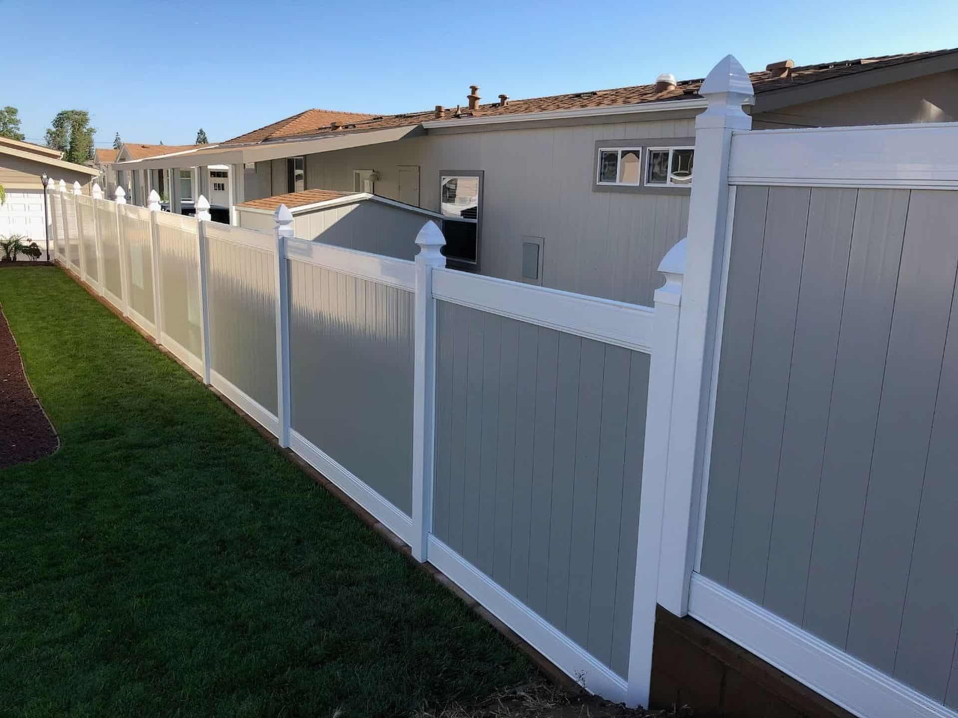 Vinyl privacy two-tone fence with gray center and white border surrounding an elevated backyard with a lush garden.