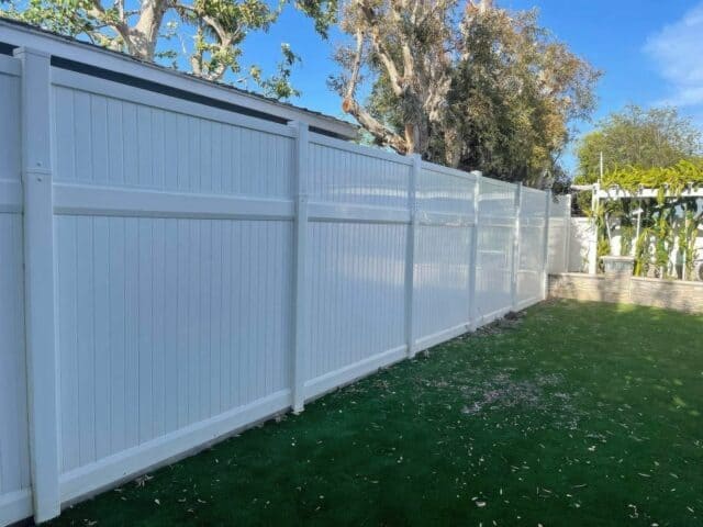 Vinyl privacy vertical fence sectioning off the lawn from the rest of the house with small vertical garden to the side