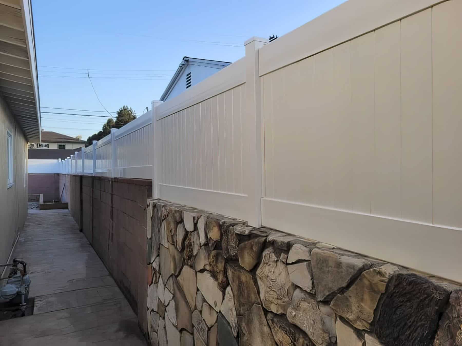 Vinyl privacy wall topper on concrete boundary wall and granite stone wall for side passage leading to backyard.