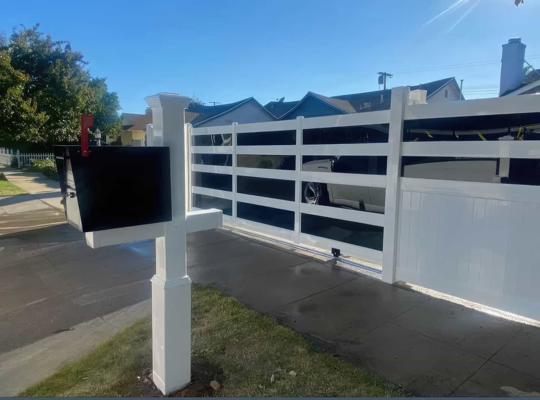 Vinyl rolling gate featuring reflective glass sections with traditional a mailbox on grassy patches beside the sidewalk.