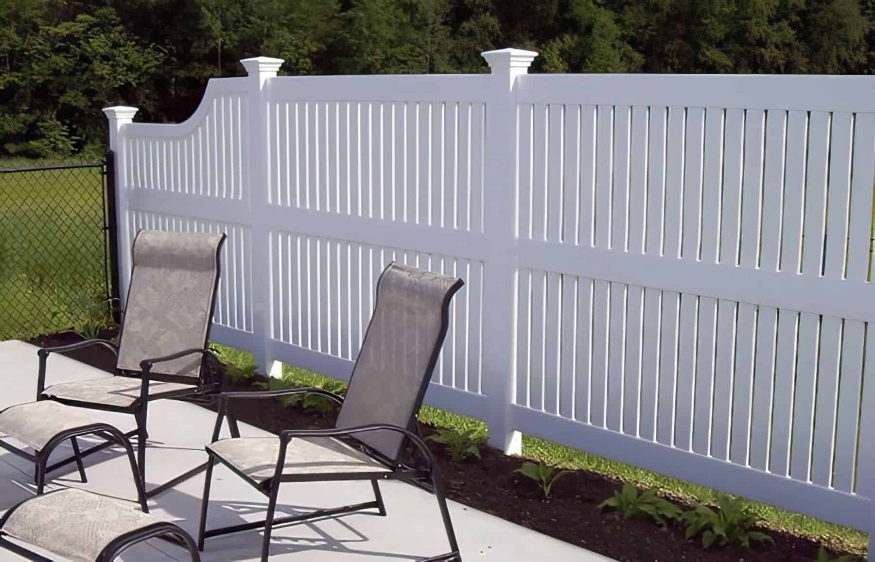Stylish vinyl semi-privacy fence next to small shrubs and short metal fence creating a boundary for the home.