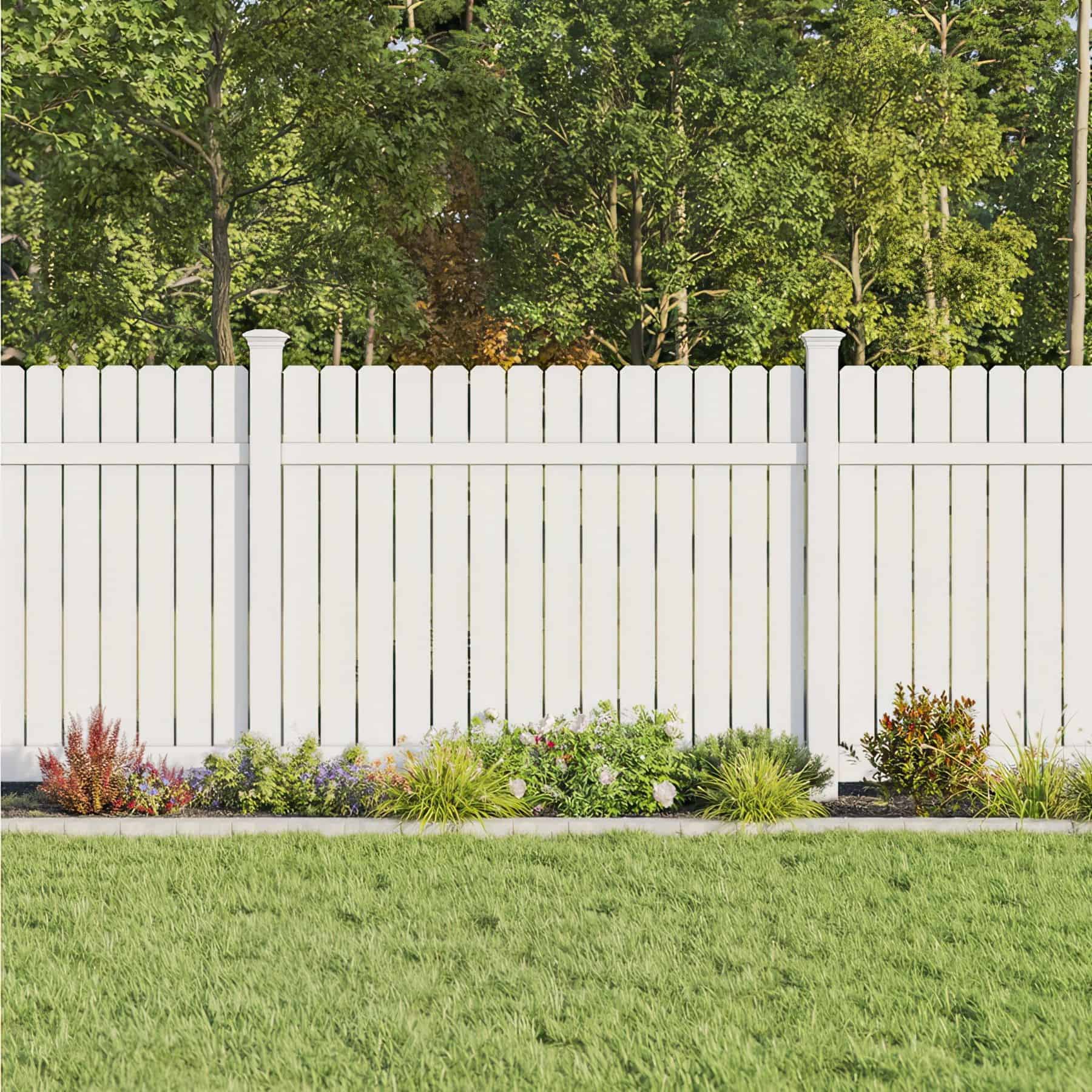 White, picket vinyl semi-privacy fence with small shrubs in front, separating the backyard garden from the forest.