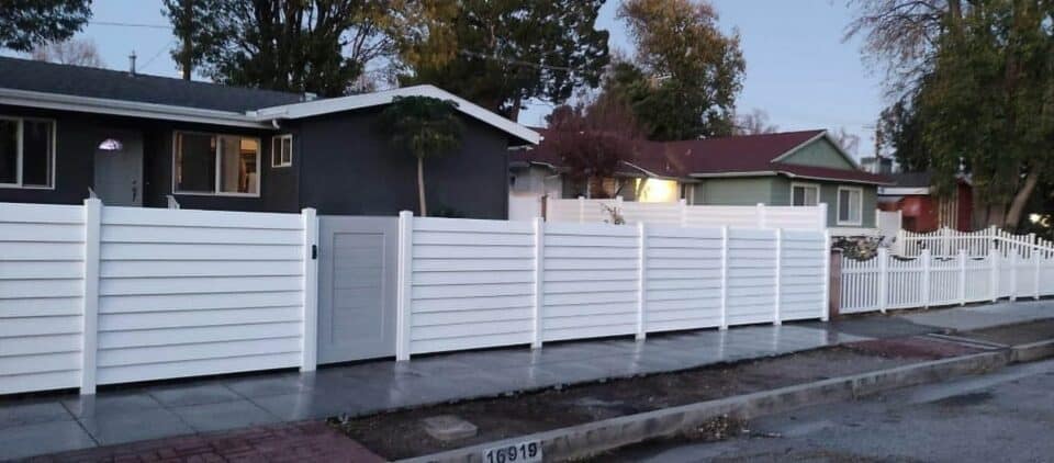 Vinyl semi-privacy fence with gray gate leading from concrete sidewalk into ranch styled townhouse