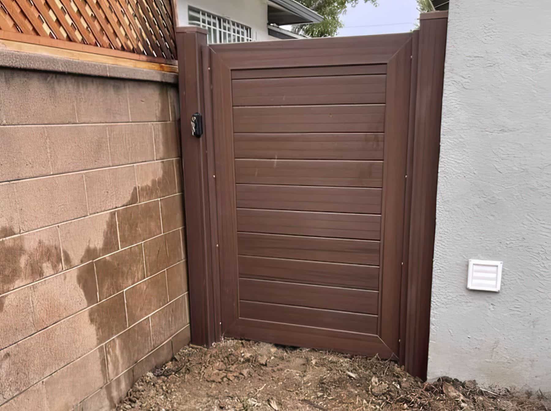 Pristine brown vinyl single side gate between olive white wall and concrete brown wall with wooden trellis on top.