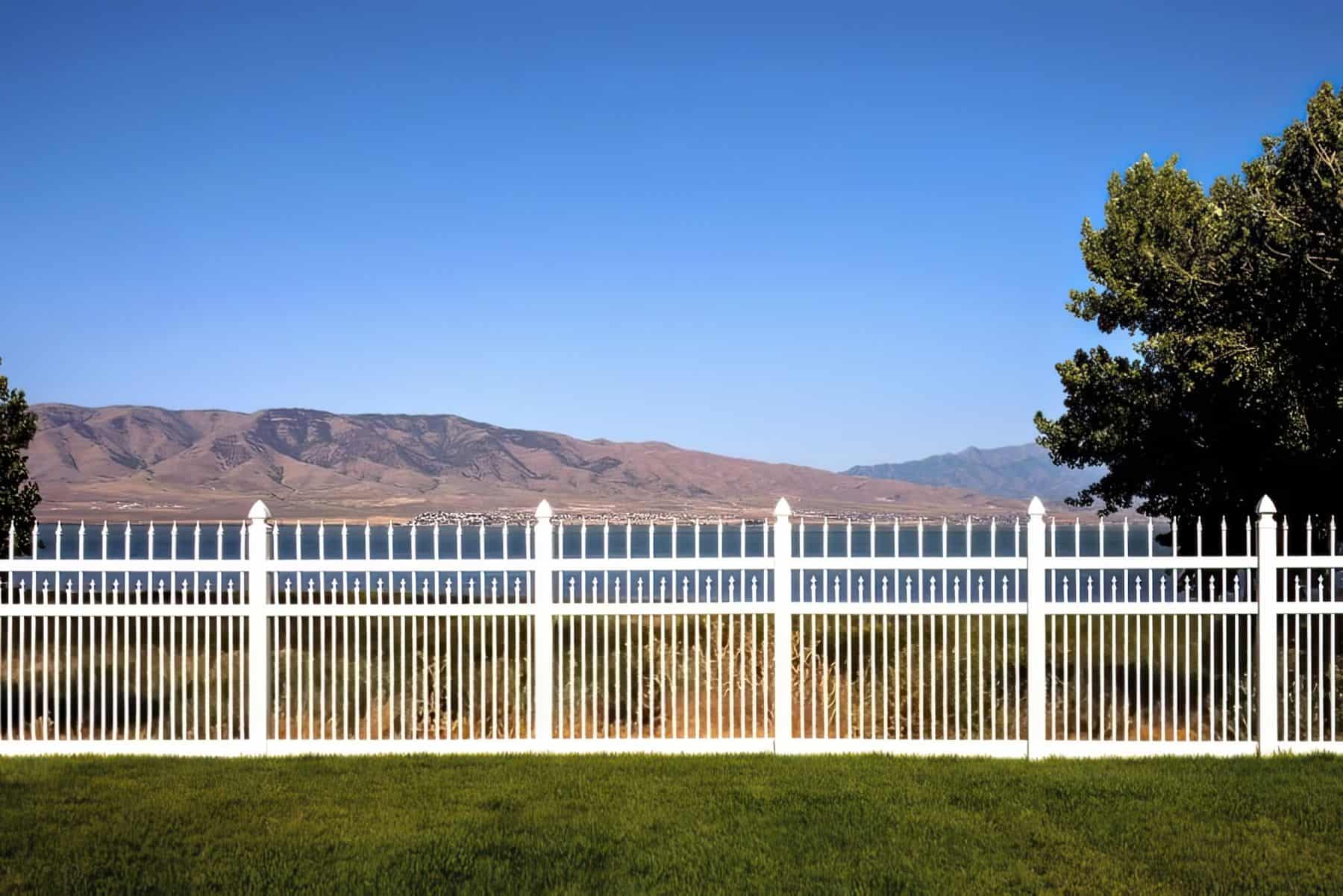 Majestic vinyl picket fence framing serene lake & majestic mountains, defining a picturesque green boundary.